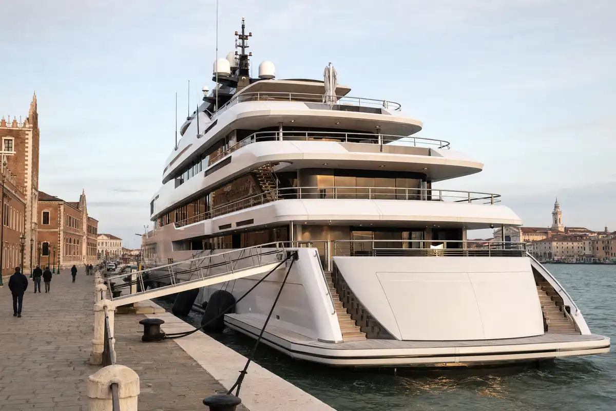 Megayacht bianco a più ponti ormeggiato lungo la riva a Venezia, con passerella e palazzi sullo sfondo