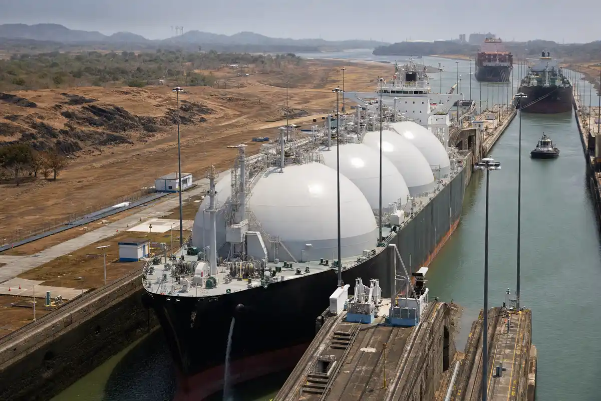 Gasiera con grandi serbatoi bianchi nelle chiuse del Canale di Panama, con altre navi in attesa sullo sfondo